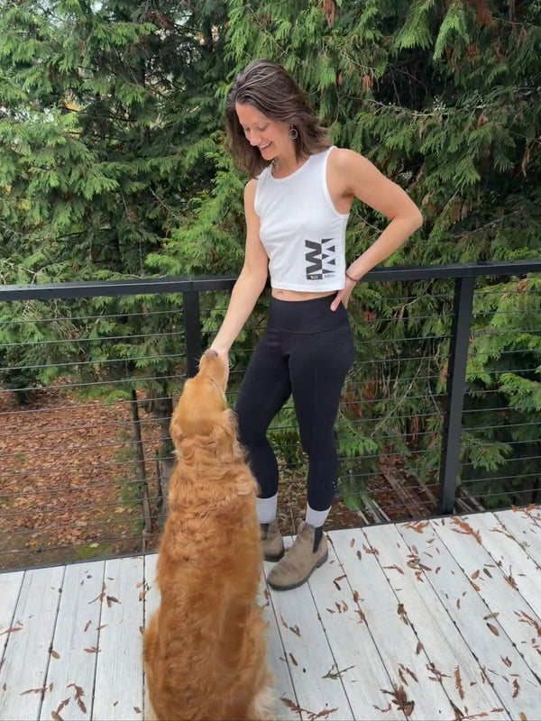 Woman in athletic wear standing on a deck with a golden retriever