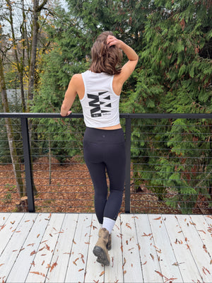 Person in athletic wear standing outdoors with trees and a fence in the background